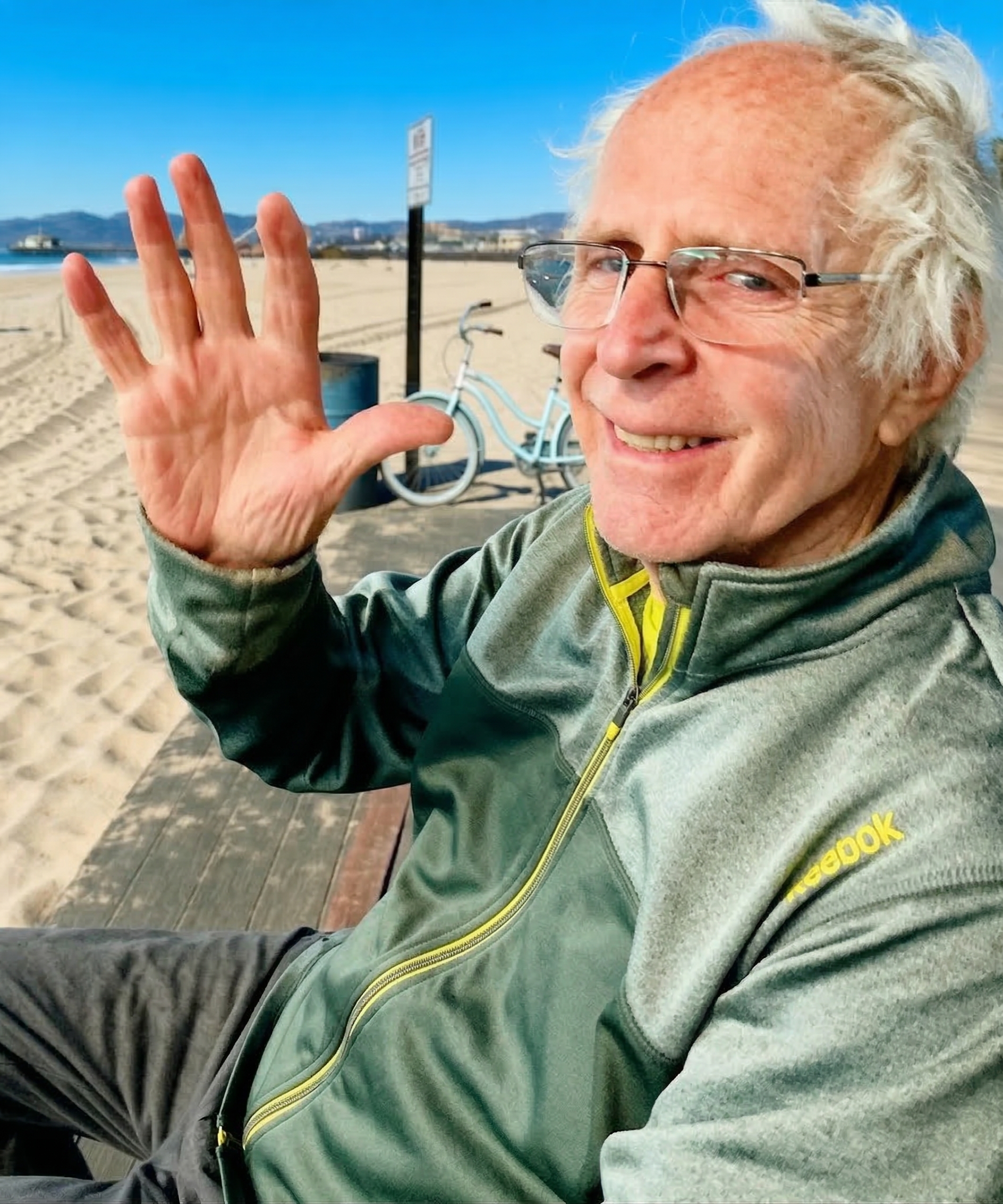 Frank Curtis smiling and waving, outdoors at bay street at sunset